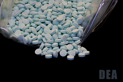 Blue fentanyl pills spill out of a clear bag.